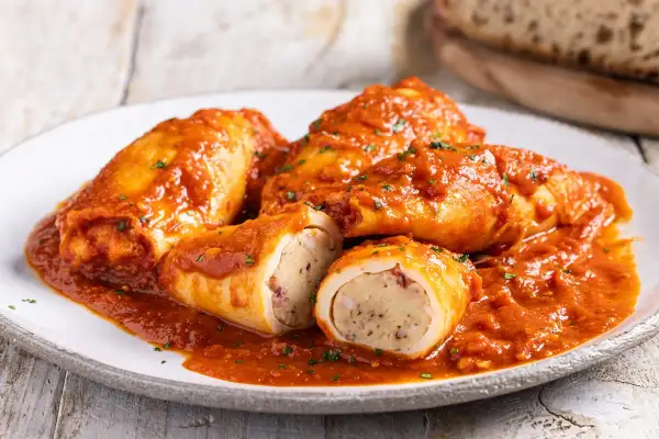 Calamari ripieni in padella, succulenti e ricoperti da un sugo rosso, pronti per essere gustati.