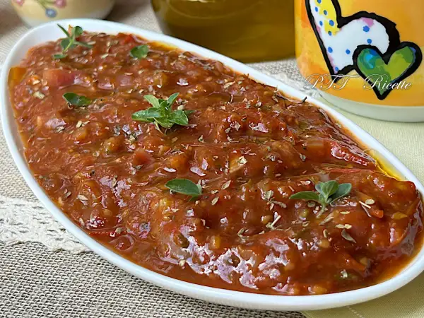 Sugo con pomodorini freschi, profumato con erbe aromatiche, servito in una ciotola bianca.