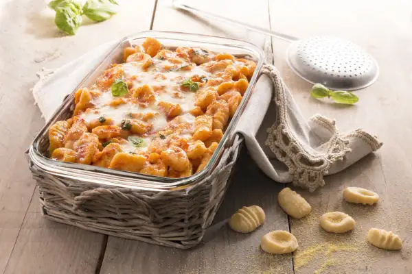 Gnocchi di polenta al forno, dorati e filanti, con basilico fresco. Un piatto invitante pronto per essere gustato.