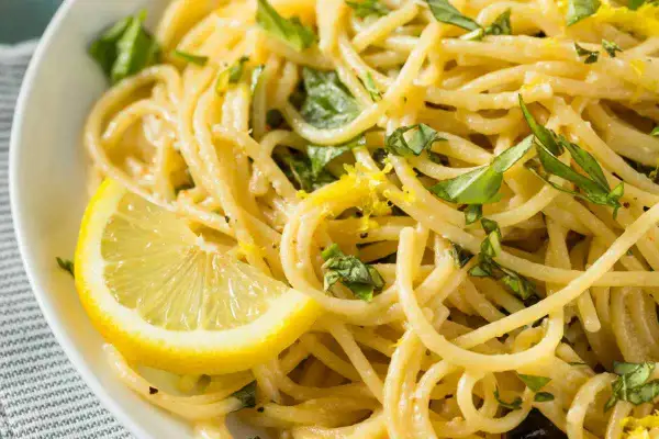 Spaghetti al limone, un sapore di Costiera Amalfitana. Pasta fresca con scorza di limone e basilico, guarnita con una fetta di limone.