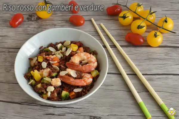 Un piatto di riso rosso con gamberi e verdure, un'idea per ricette veloci e gustose. Mandorle a lamelle completano il tutto.