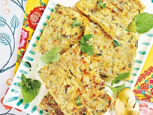 Fette dorate di polpette vegetariane, croccanti fuori e morbide dentro, guarnite con erbe fresche su un piatto decorato.