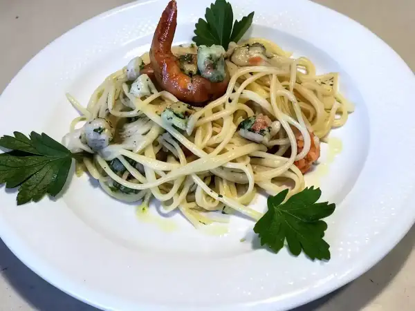 Un piatto invitante di pasta con mazzancolle, condita con erbe fresche e un filo d'olio.