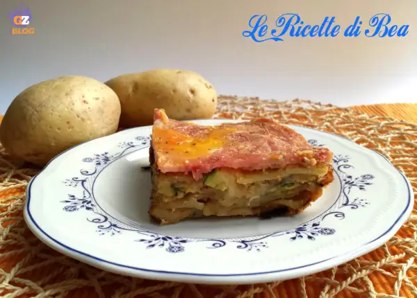 Una fetta di parmigiana di zucchine e patate, con prosciutto e formaggio fuso, servita su un piatto decorato.
