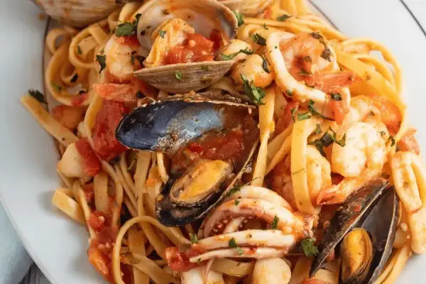 Un piatto invitante di scialatielli allo scoglio, con gamberi, cozze, vongole e calamari in un sugo rosso.