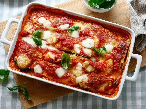 Parmigiana di zucchine, un classico delle ricette della nonna, cotta al forno con pomodoro e mozzarella filante, guarnita con basilico fresco.